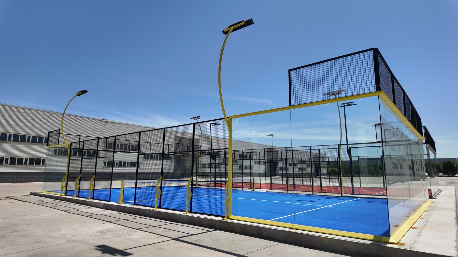 Fortune padel court with a yellow structure assembled next to the manufacturing plant